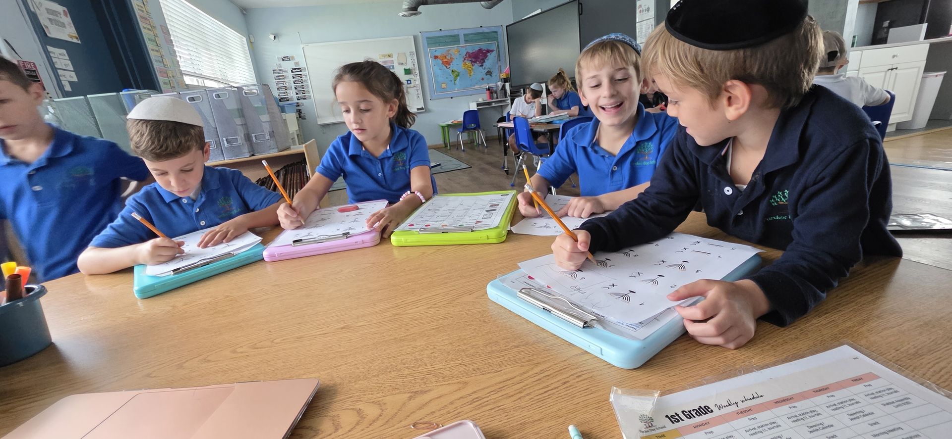 Students smiling over their practice sheets at a classroom table