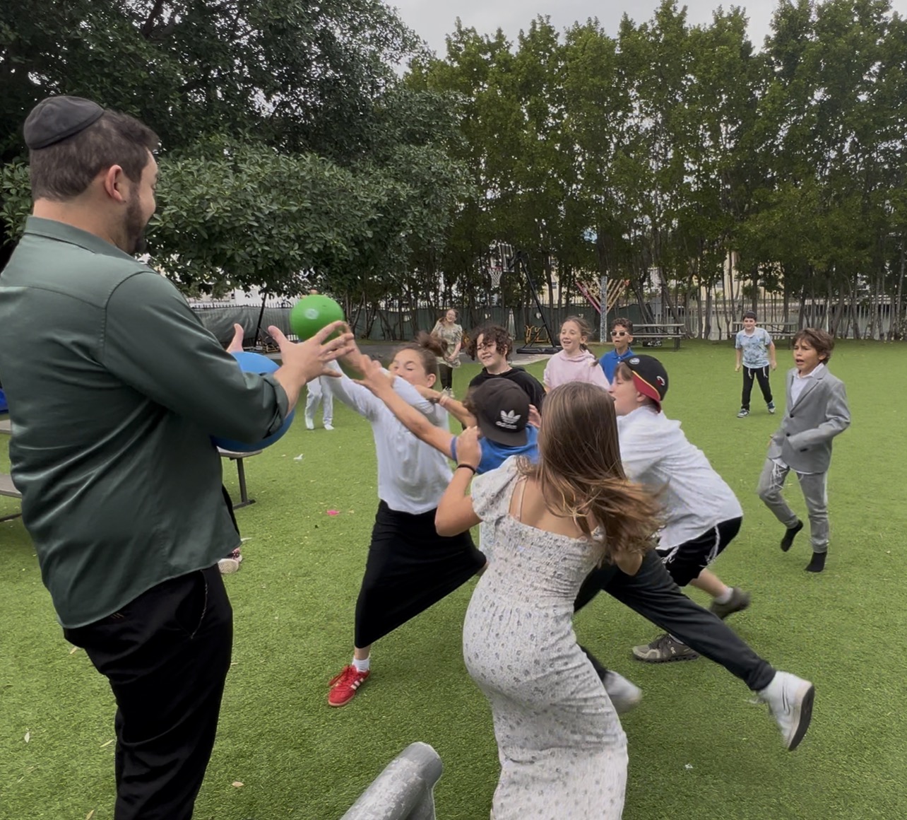 Students and a teacher playing a ball game on the field