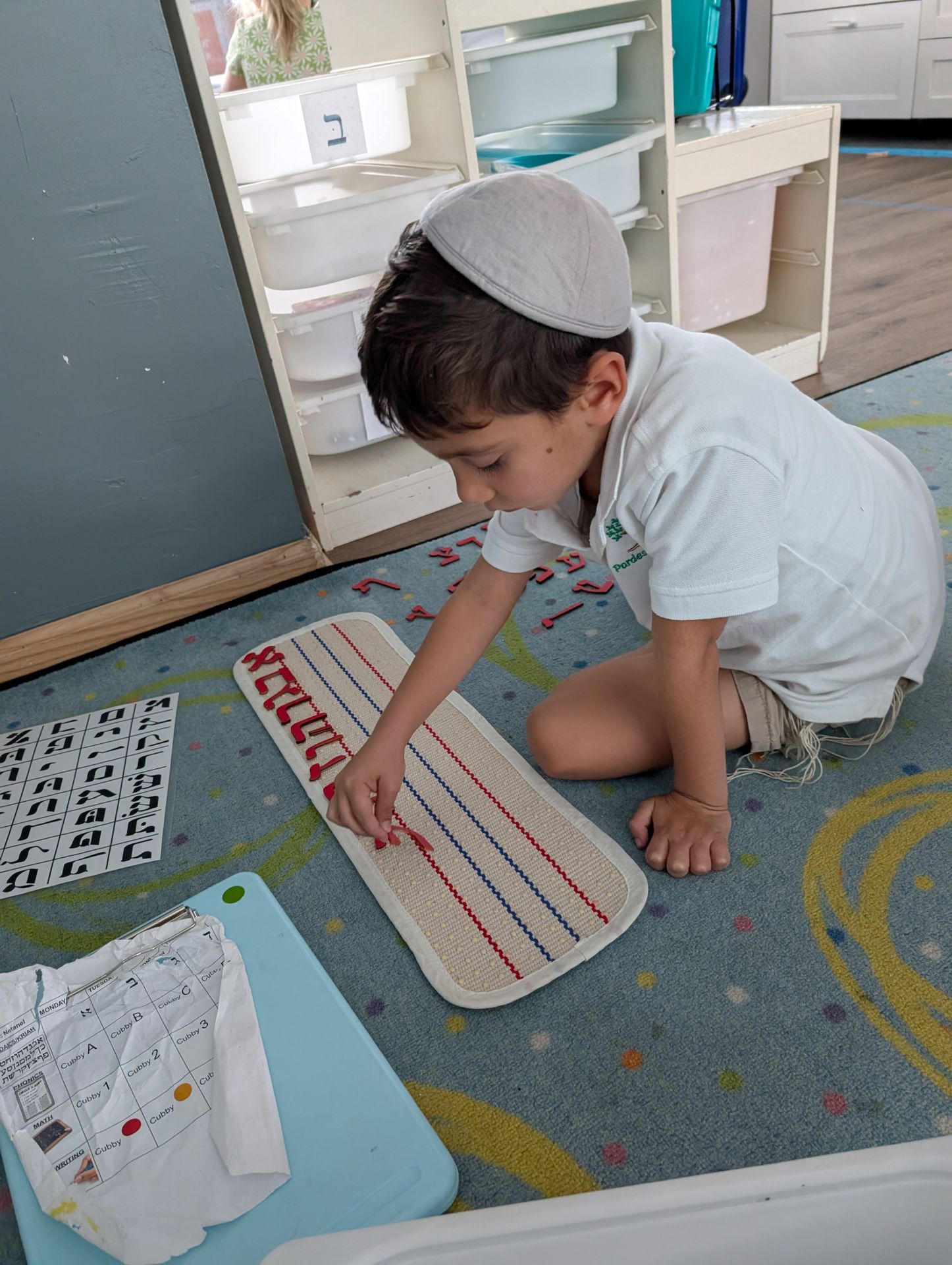 A student practicing Hebrew letters on the rug