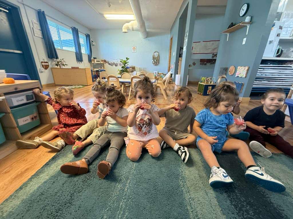 Gan Katan children sharing a fruit snack on the rug