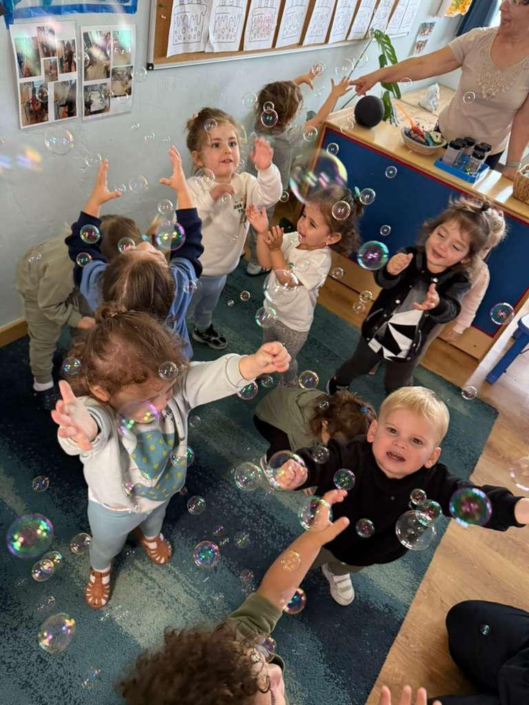 Gan Katan children reaching for bubbles
