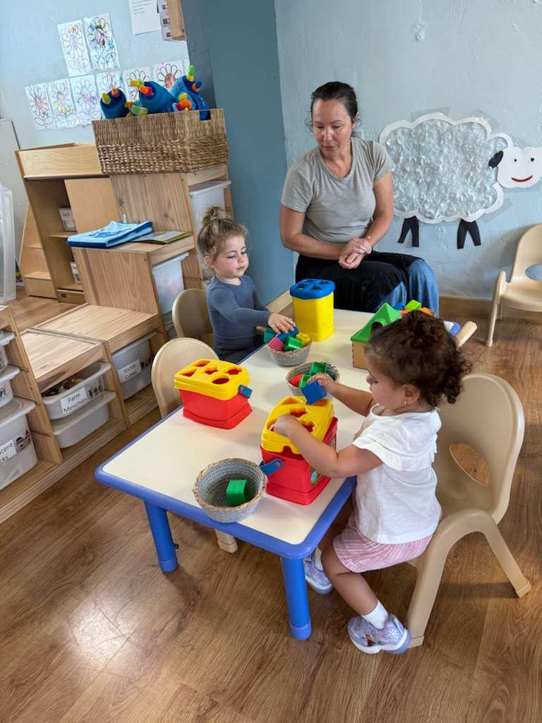 A teacher with a toddler playing with shape sorters